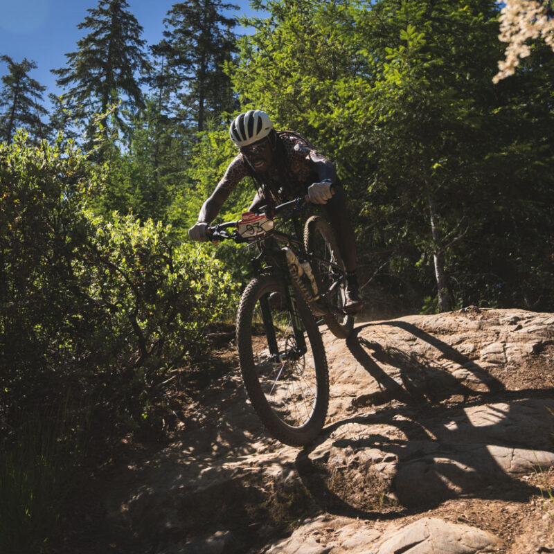 mountain biker rolling down a rock during the bc bike race