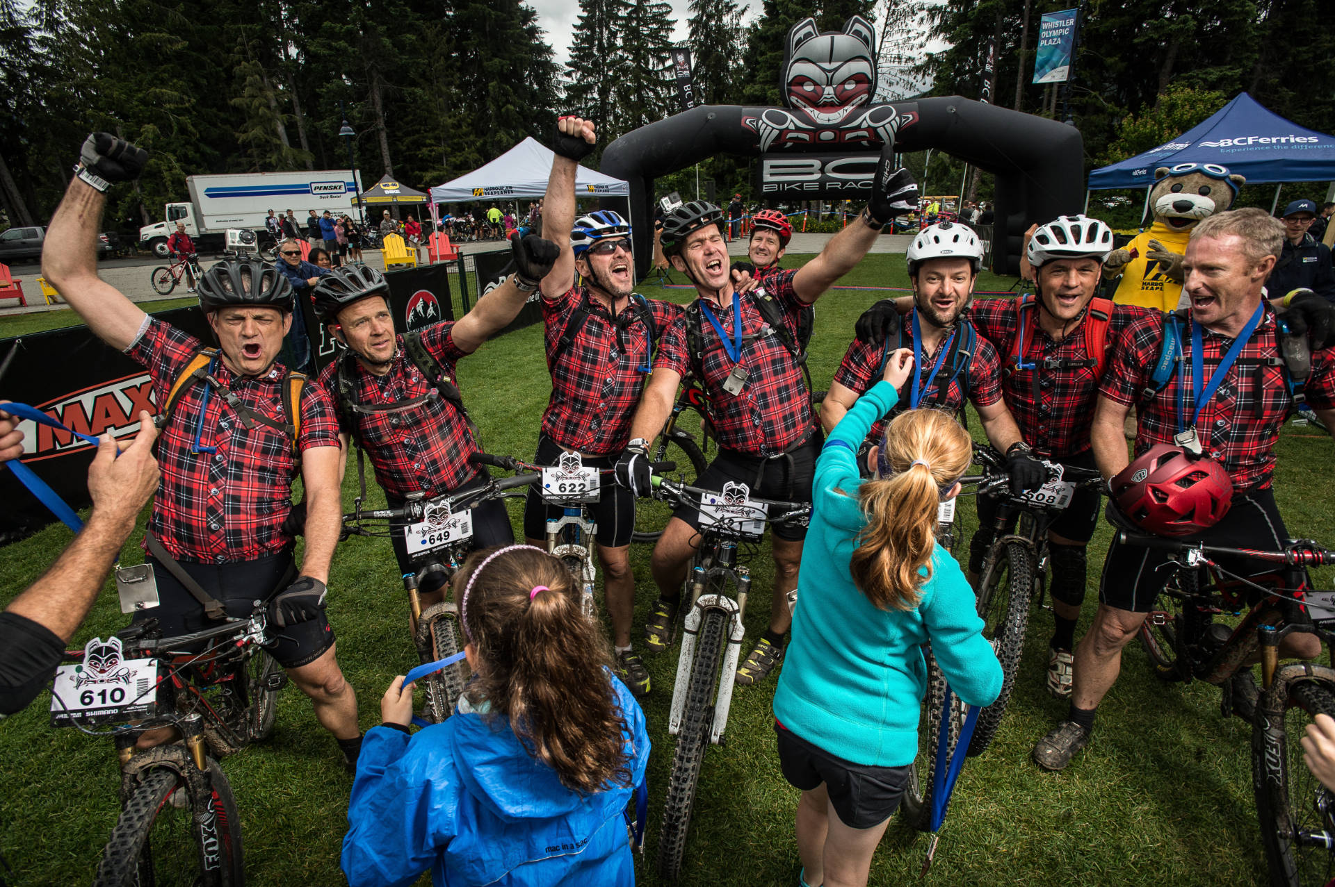 group of mountain bikers in plaid jerseys receiving their belt buckles at day 7 of the BC Bike Race